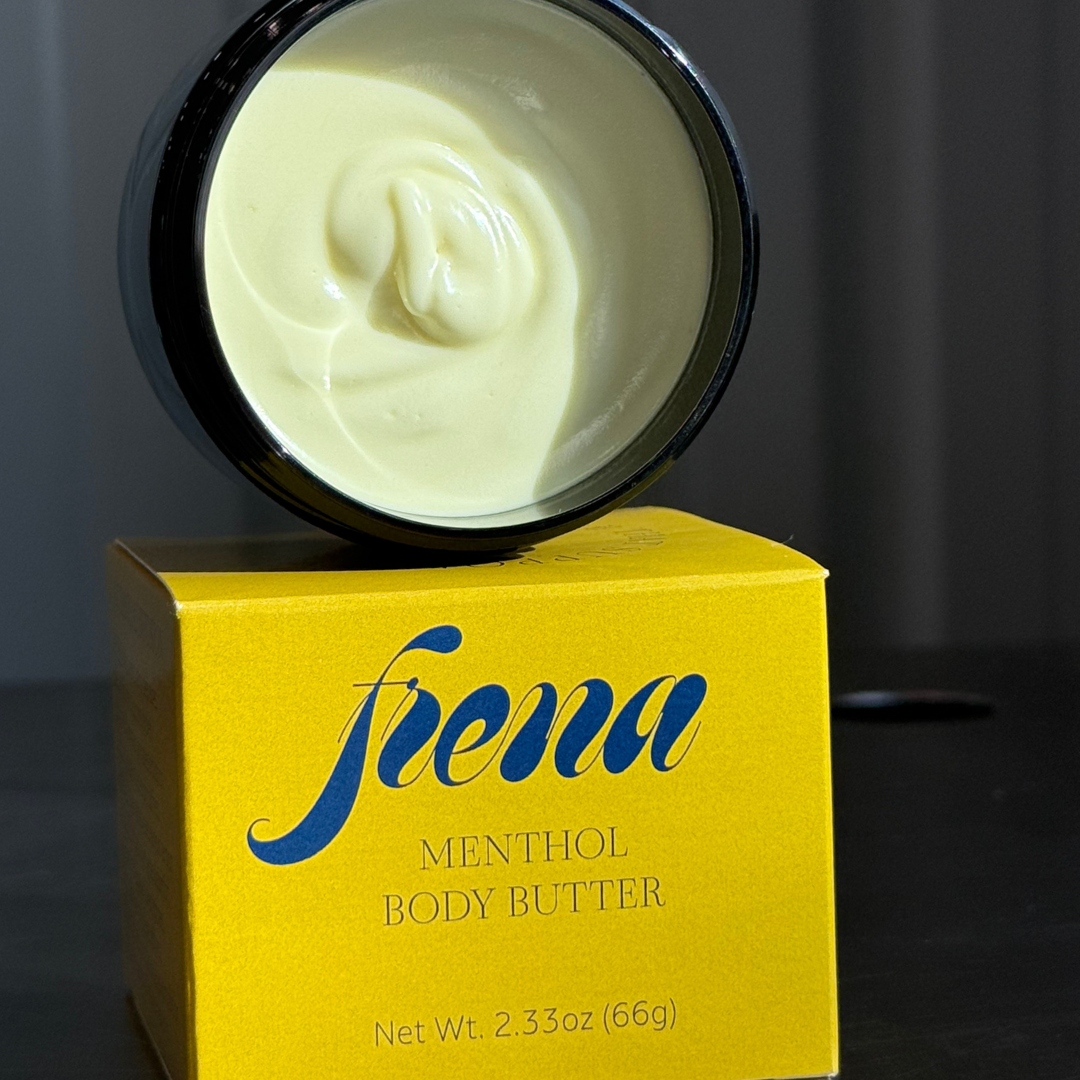 Open jar of Frena’s Menthol Body Butter in the sunlight sitting on the box it came in